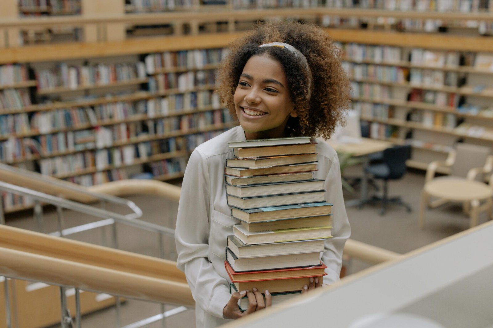 A smiling student carrying stack of books in the library